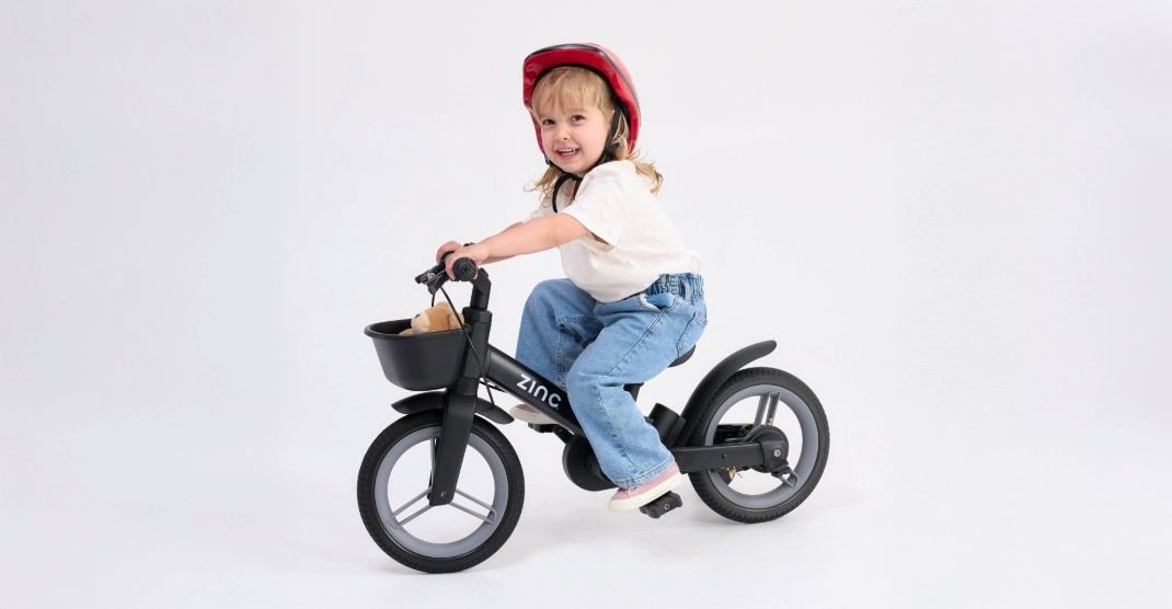 Zinc multifunctional bike being ridden by a small girl in red helmet.