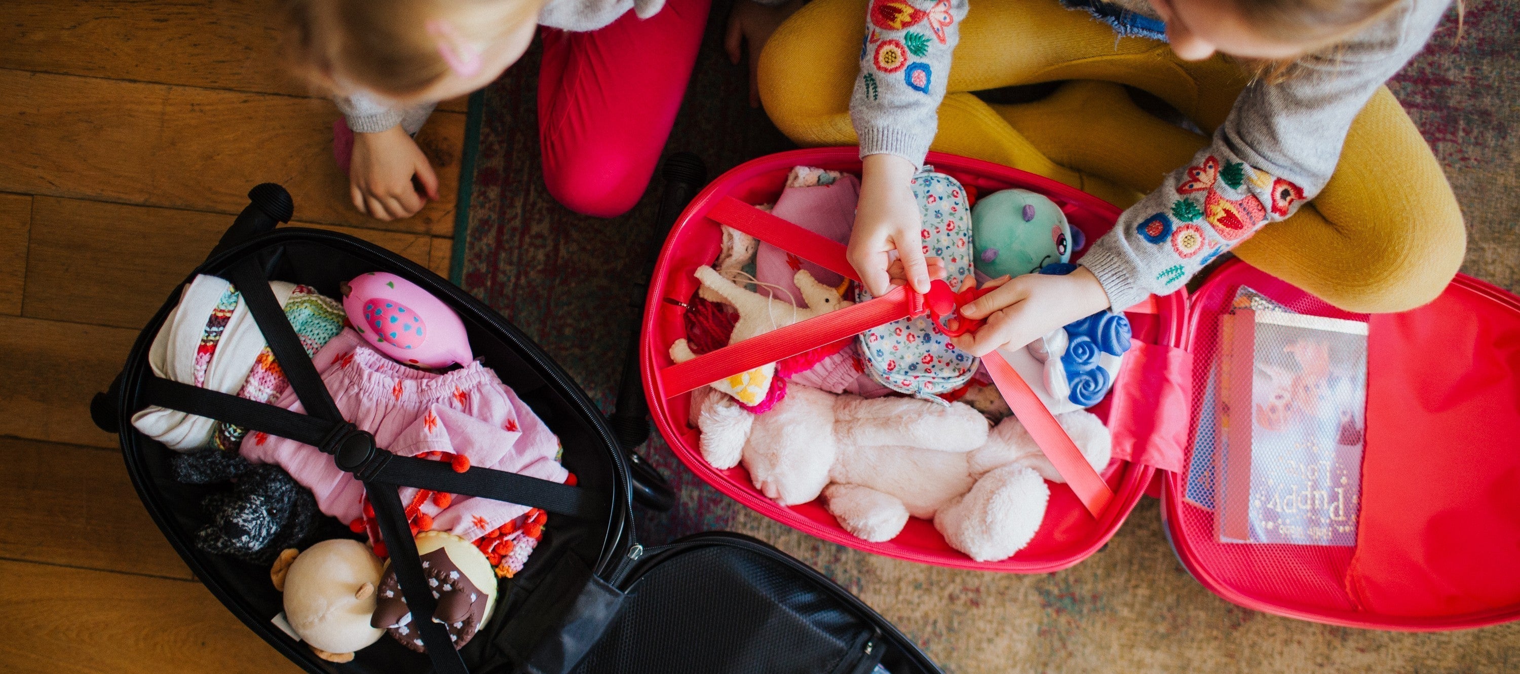 Two suitcases being backed with toys.
