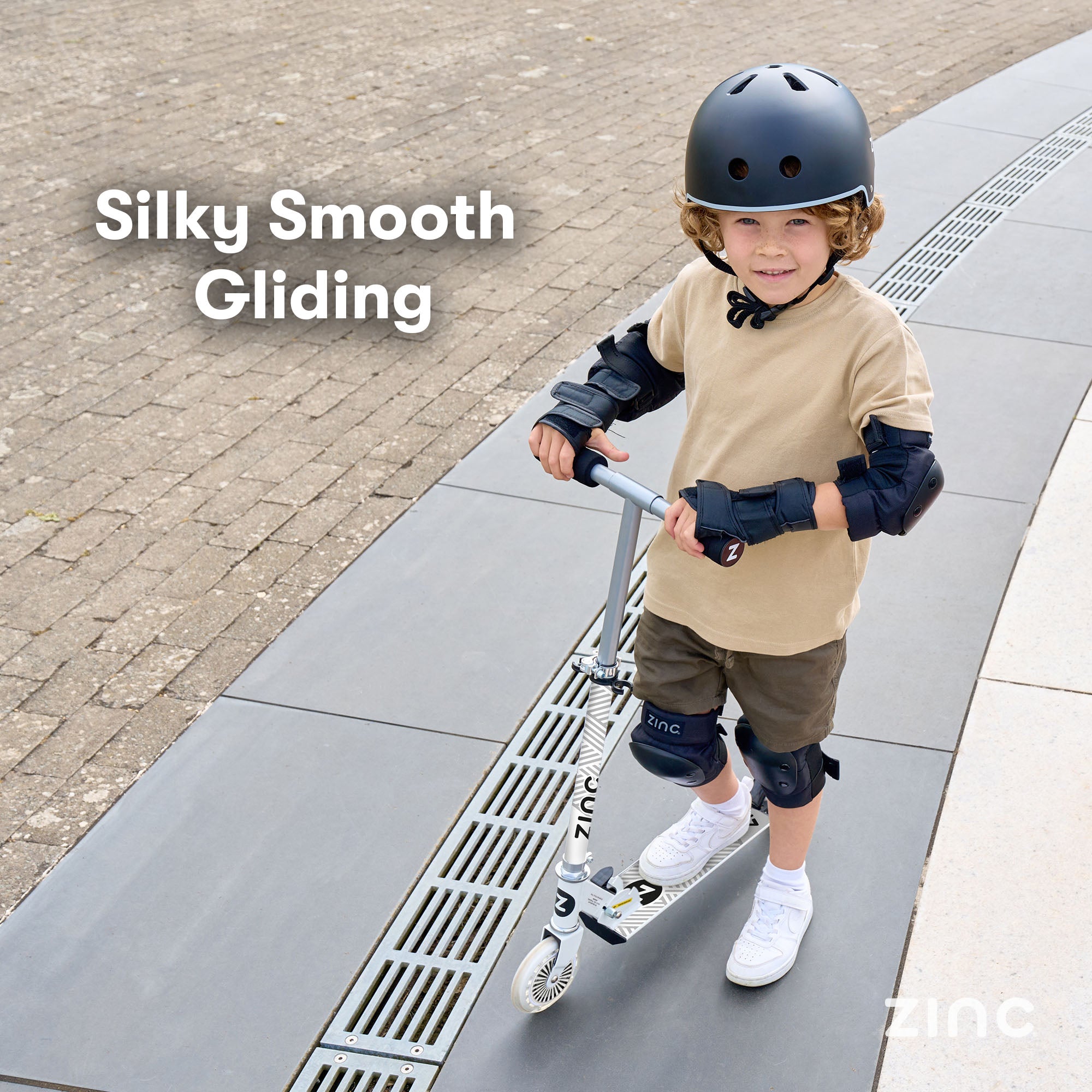 Young rider with helmet, knee pads and elbow pads on folding scooter showing essential protective gear