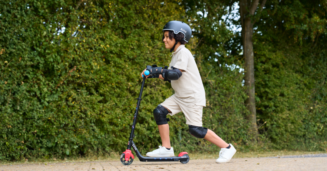 Child riding Marvel Spider-Man electric scooter wearing safety helmet and protective gear