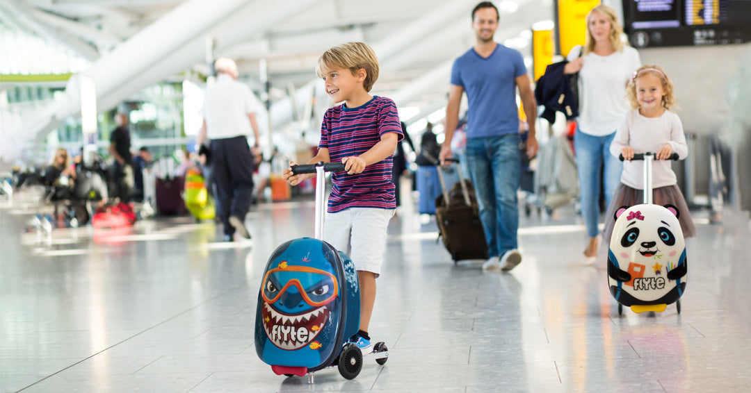 Boy and girl scooting in an airport on Flyte Scooter Suitcase with Shark and Panda designs