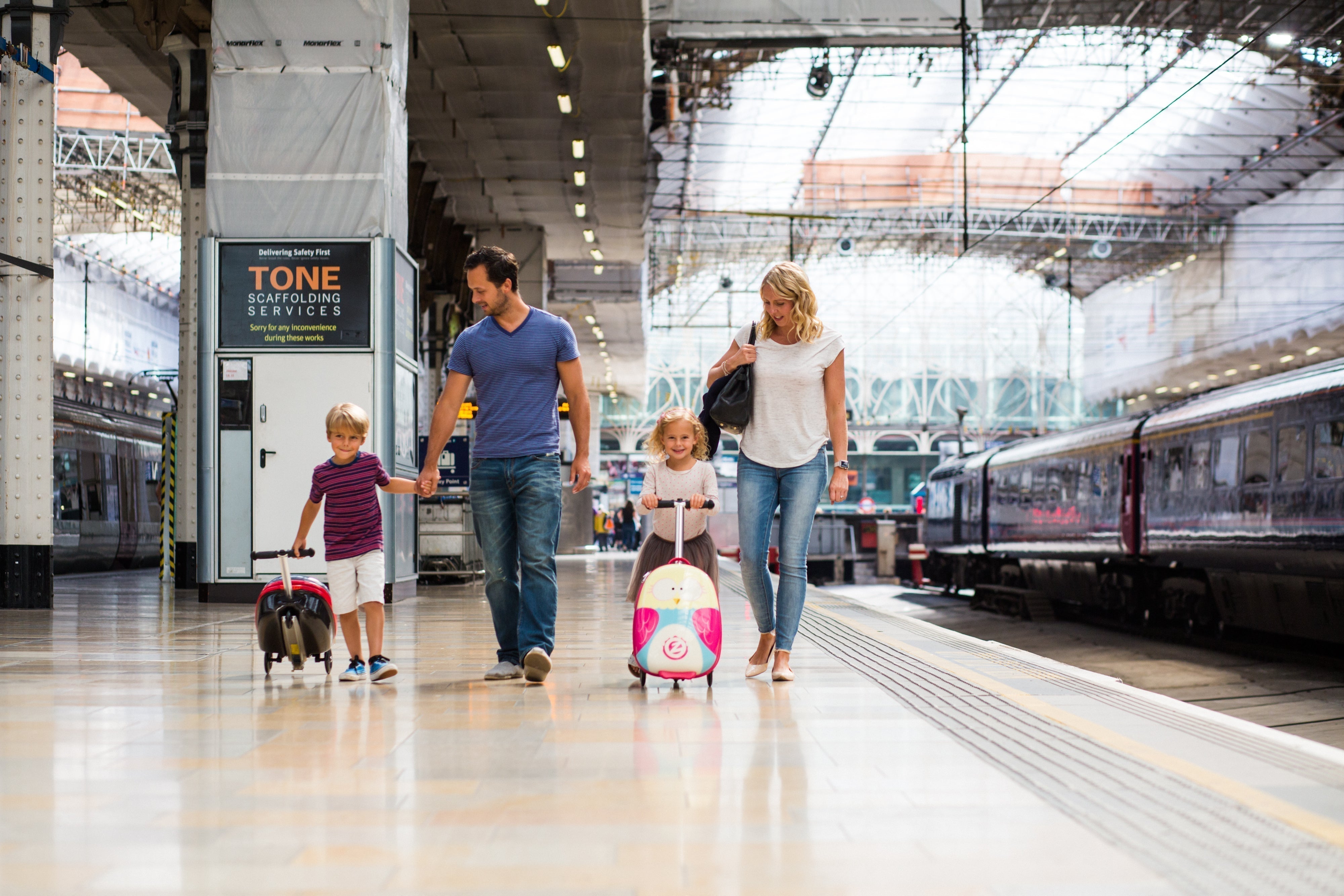 Family walking through a train station with their Flyte Scooter suitcases.