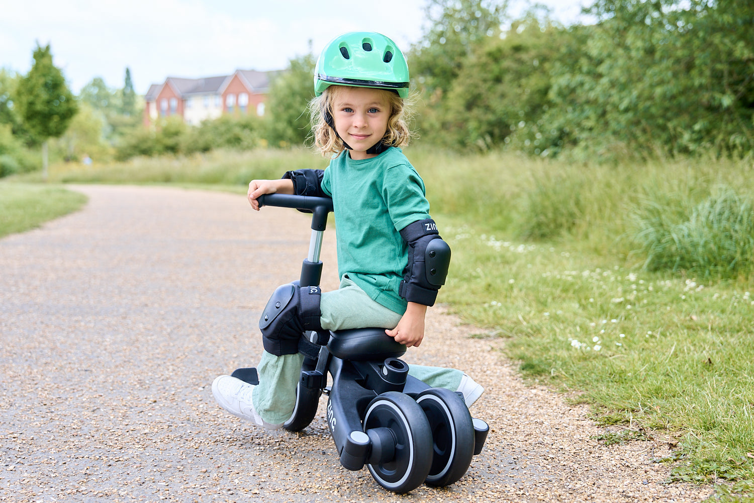 Young boy riding a Zinc Balance bike with green helmet.