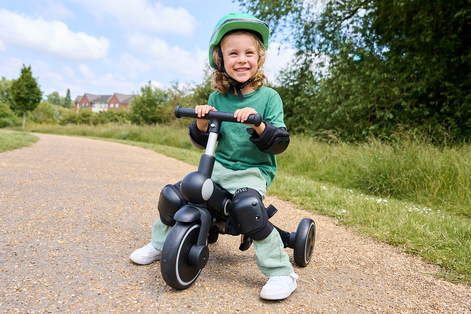 Little boy in green helmet riding the Zinc trike.