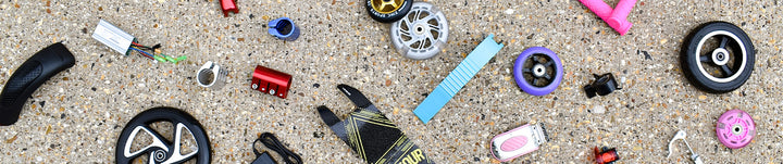 Spare scooter parts including wheels, brake parts and bolts.