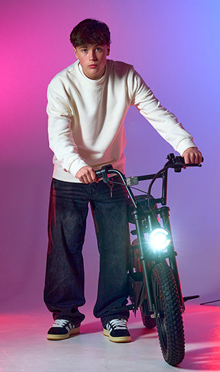 Teenage boy pushing his Zinc Electric Scooter inside studio. Featuring bright front light.