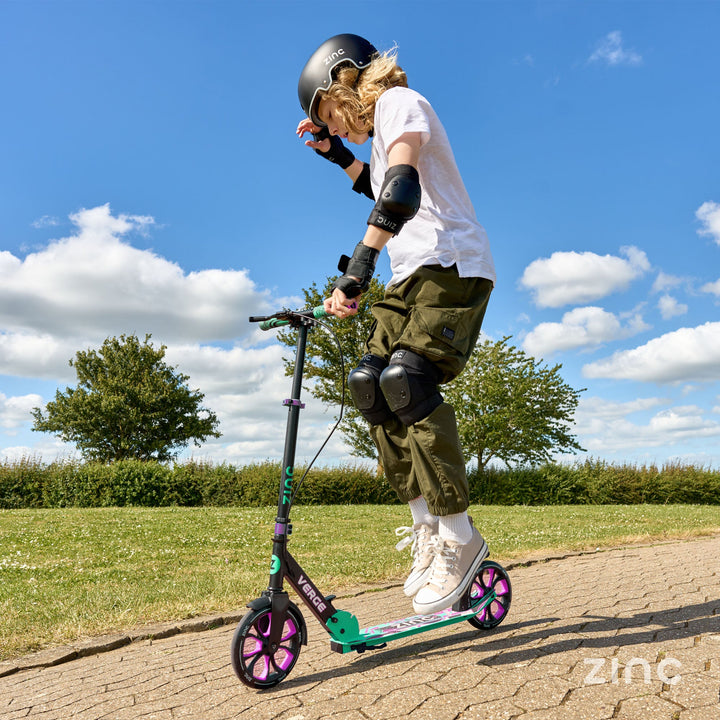 Boy riding Verge Pro scooter doing tricks while riding outside.