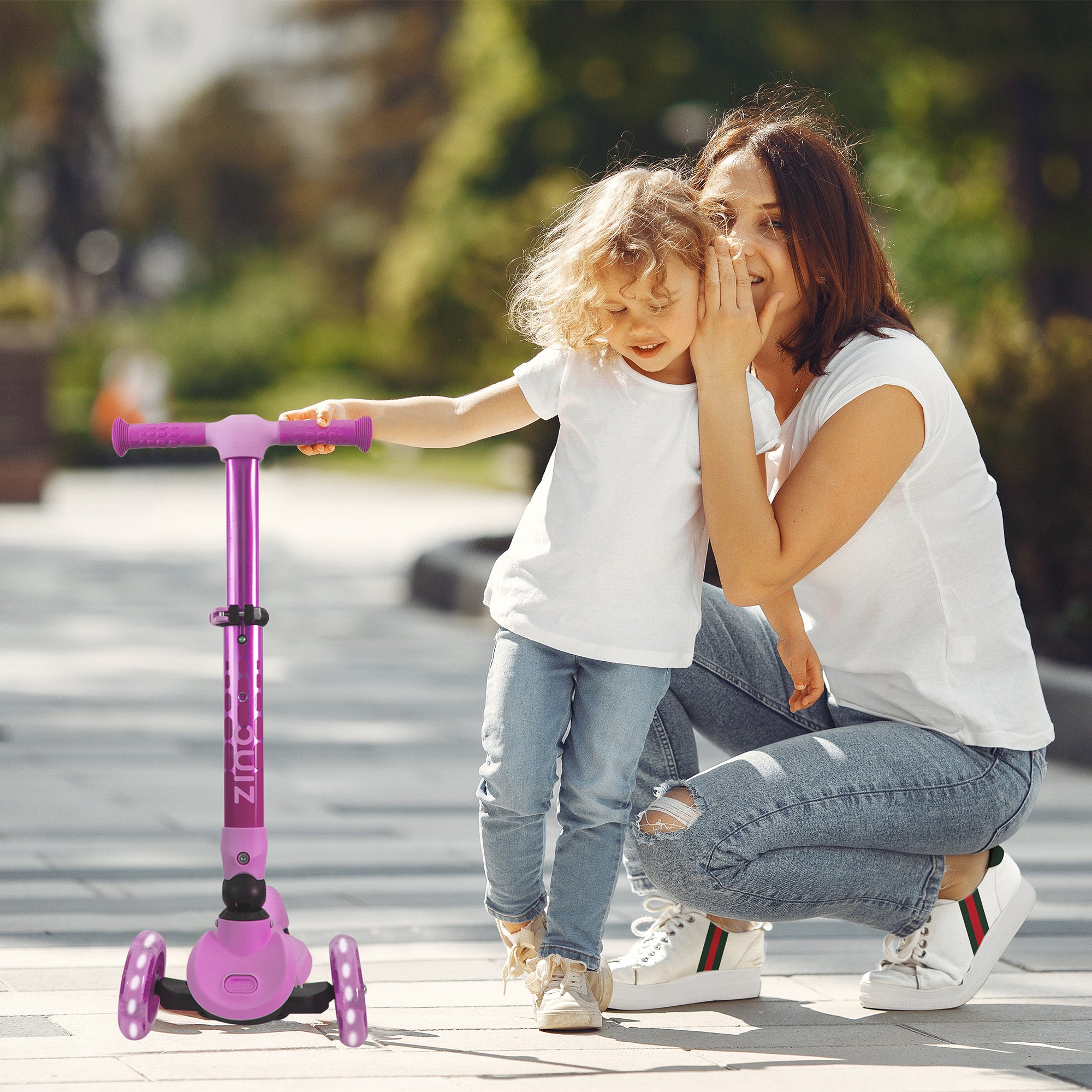 Child riding pink Zinc Flyte scooter outdoors - lifestyle shot