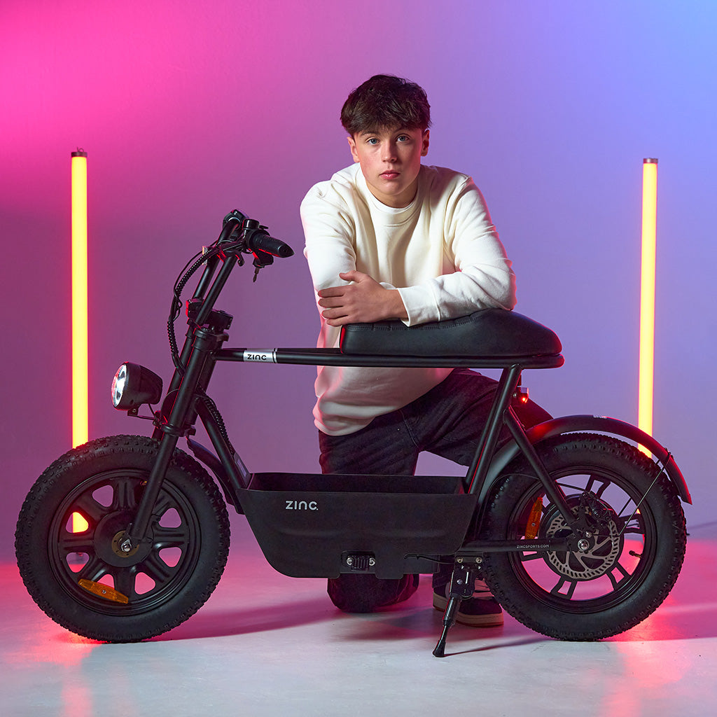 Boy posing with the Zinc Electric Sprintr scooter at a studio photoshoot.