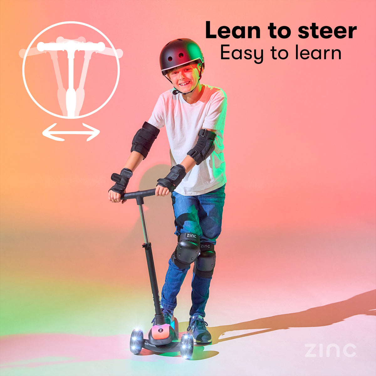 A child wearing a black helmet, elbow pads, wrist guards, and knee pads rides a pink and black T-bar kick scooter on a brightly lit studio floor with pink, orange, and green lighting. Text on the image reads 'Lean to steer Easy to learn' with a diagram showing the steering motion, and the brand name 'zinc' appears in the bottom right corner.
