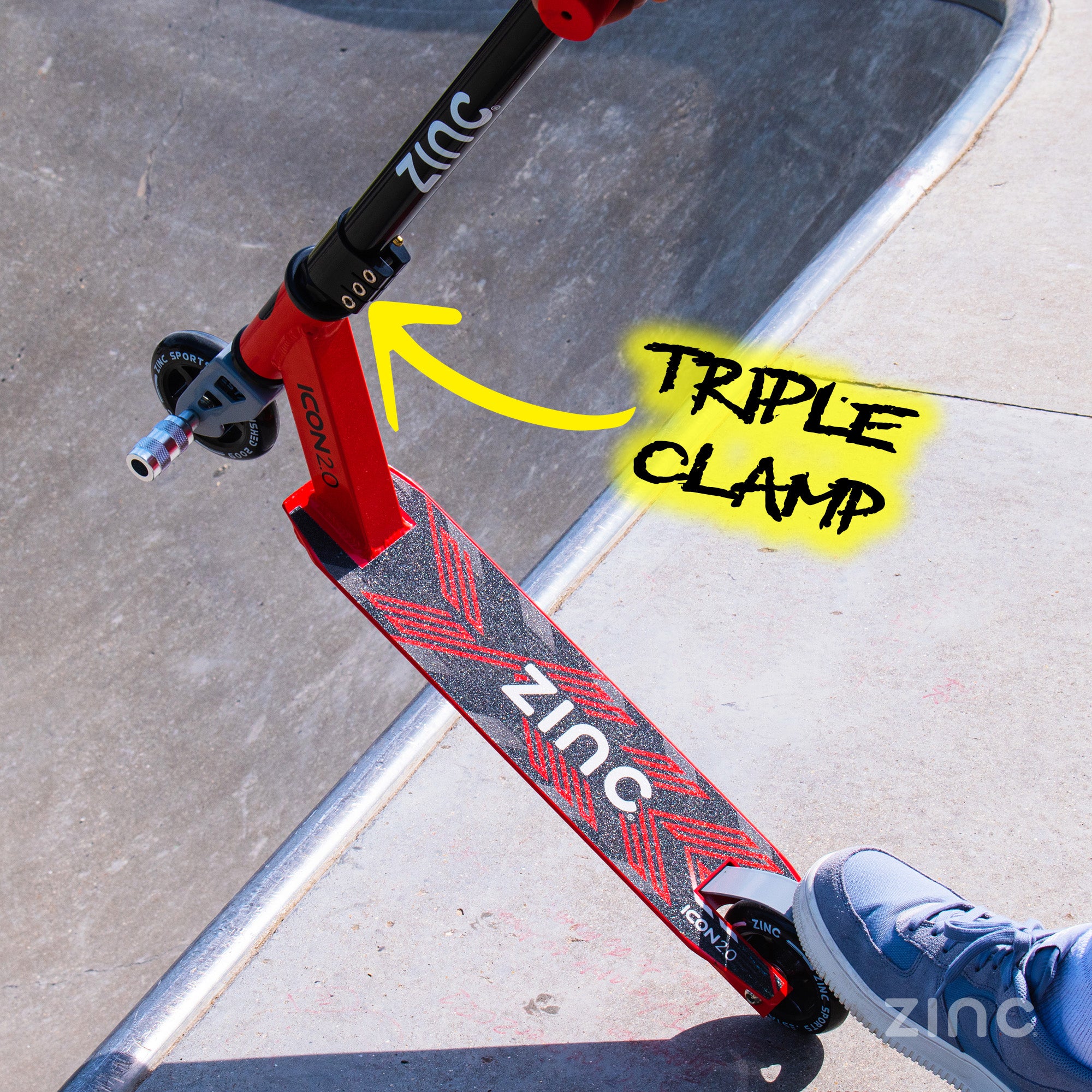 Red scooter with 'Zinc' branding on a concrete surface, highlighting the triple clamp.