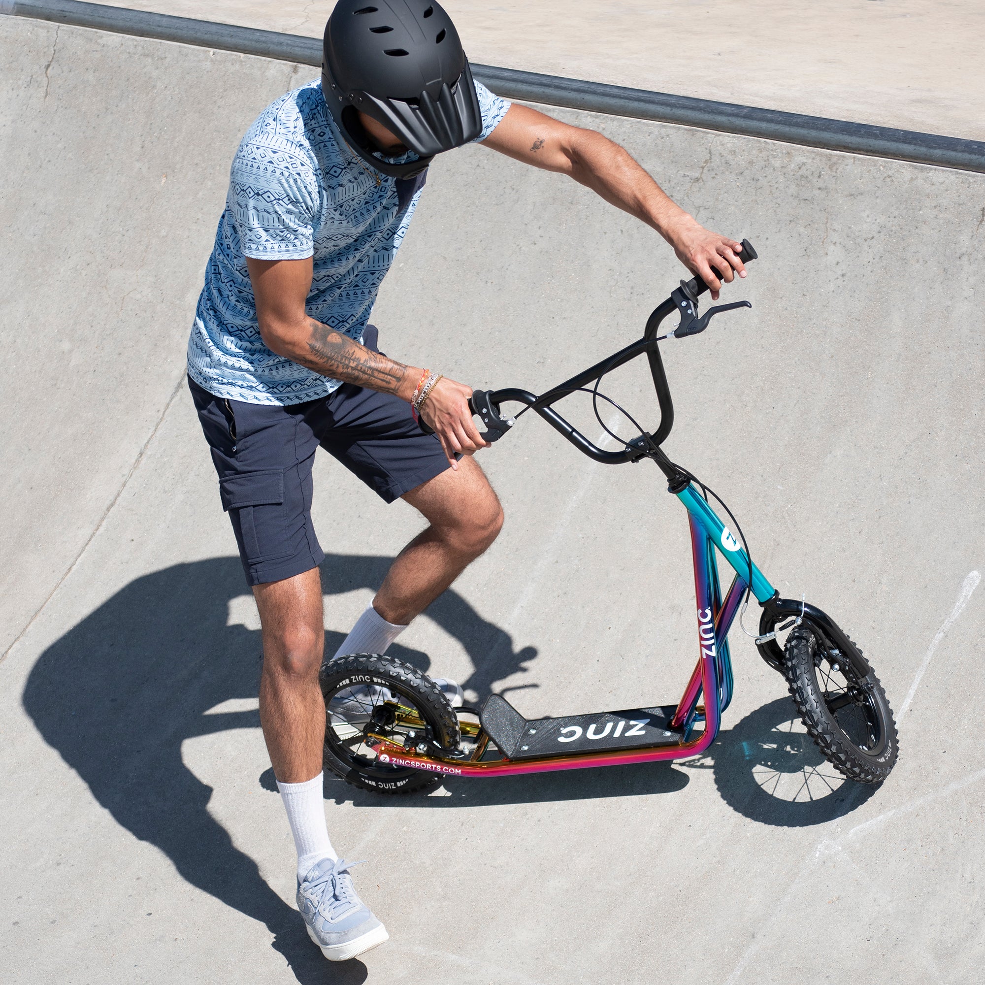Young skater riding Zinc 12 Inch BMX Scooter Neochrome Multi-colour - Skate Park Action