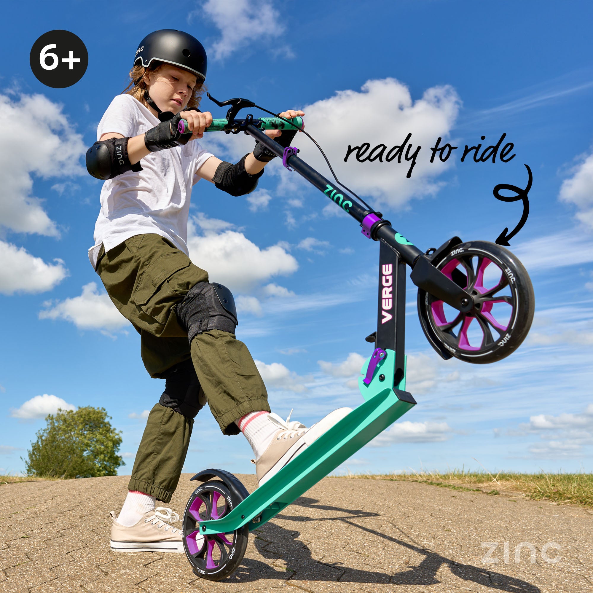 Child riding a teal scooter with pink wheels against a blue sky.