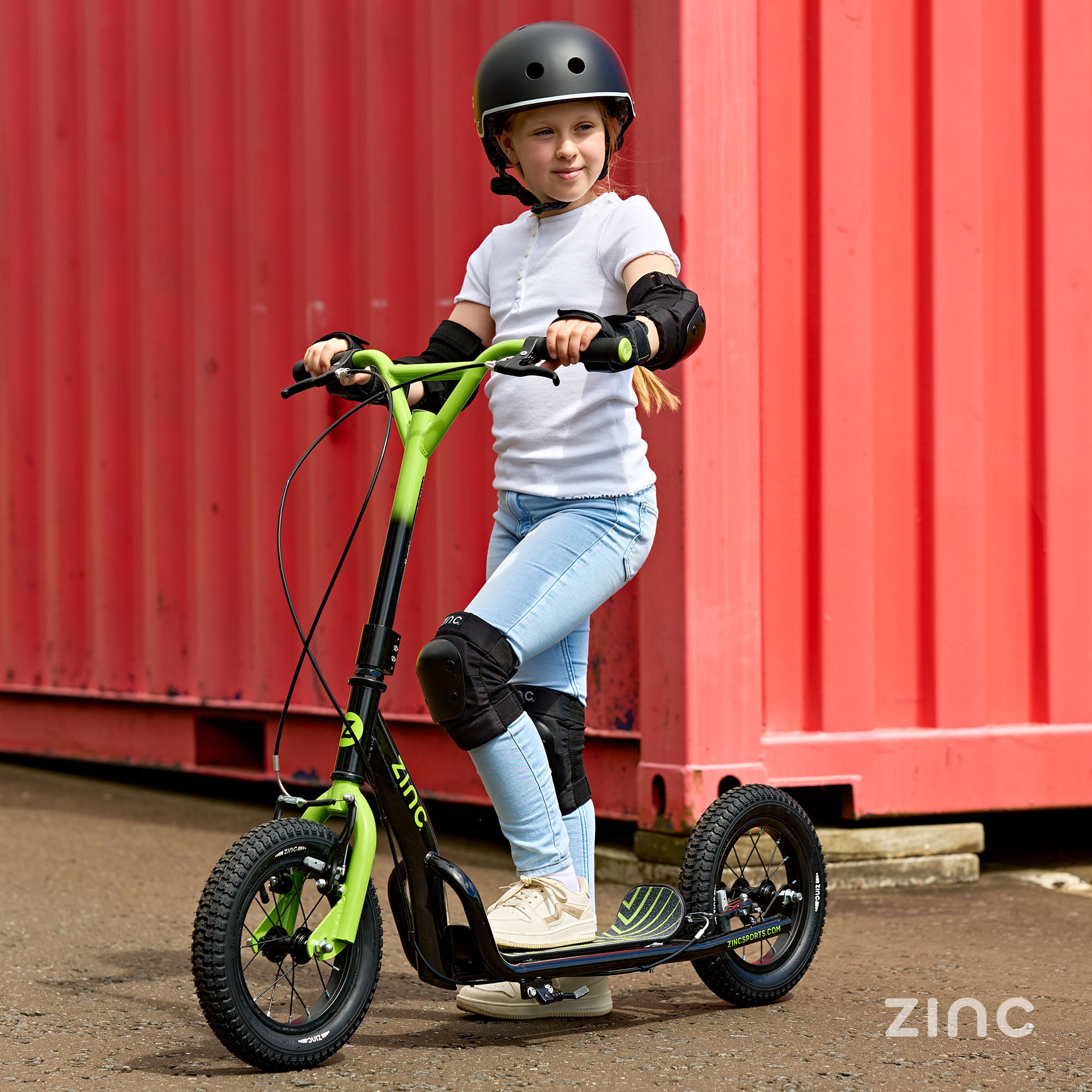 Girl posing with green Zinc Radikal 12 inch BMX scooter showcasing stylish design