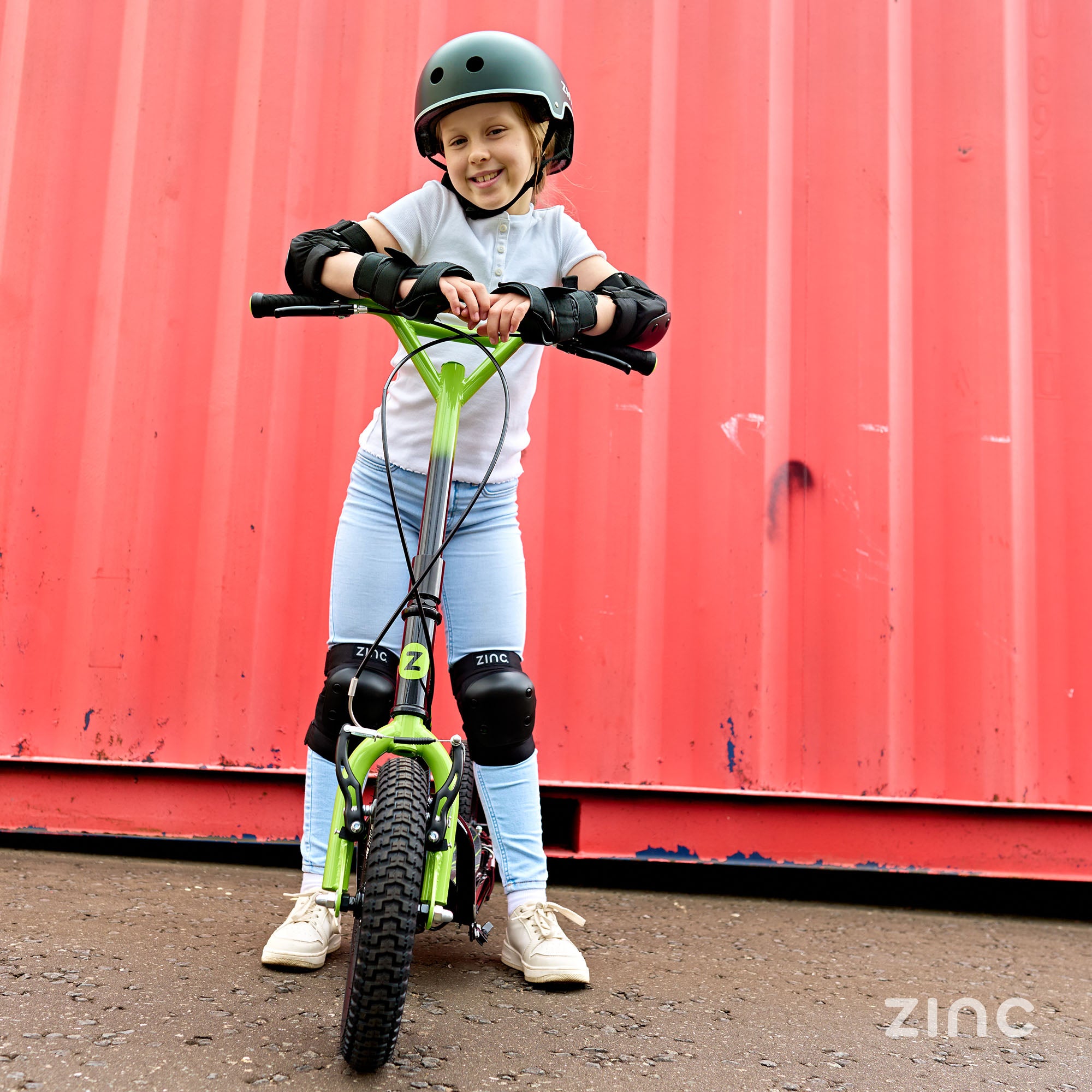 Child posing with green Zinc Radikal BMX scooter demonstrating stylish colour option and design