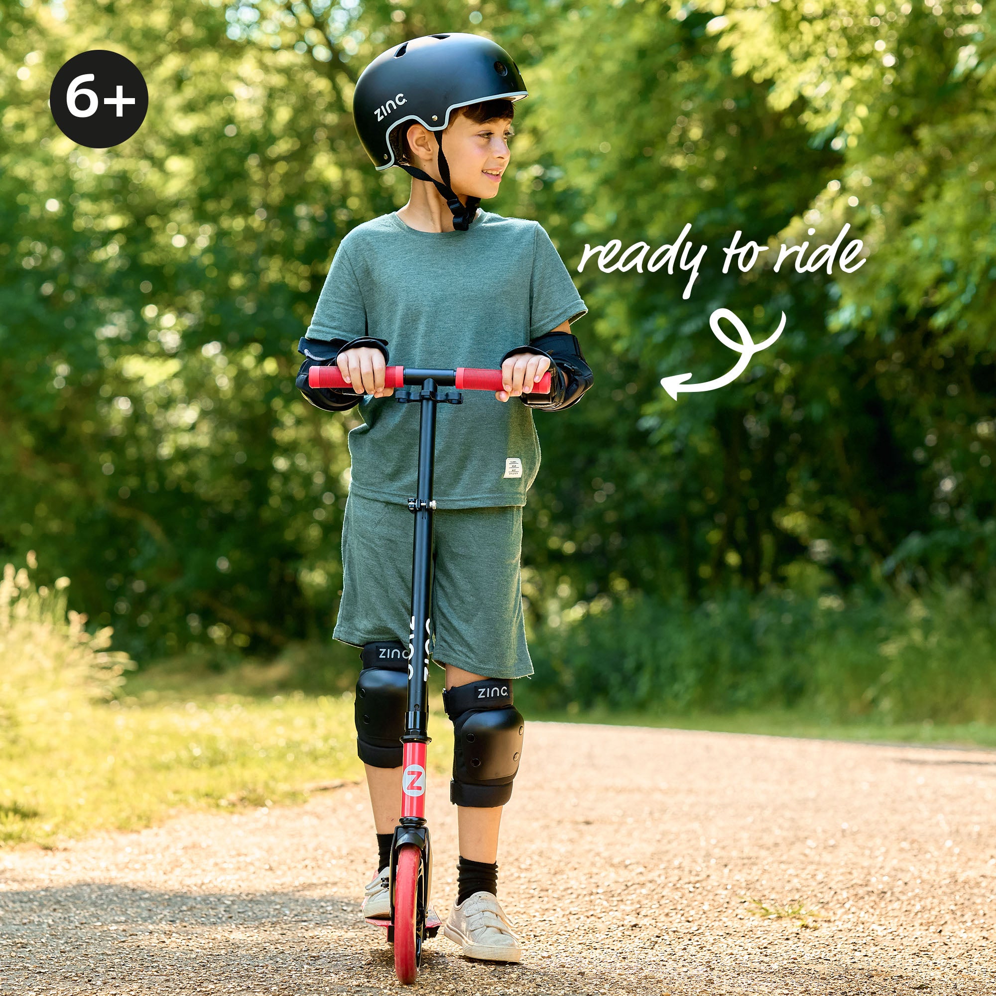 Zinc big wheel scooter in use by a young boy in full protective gear