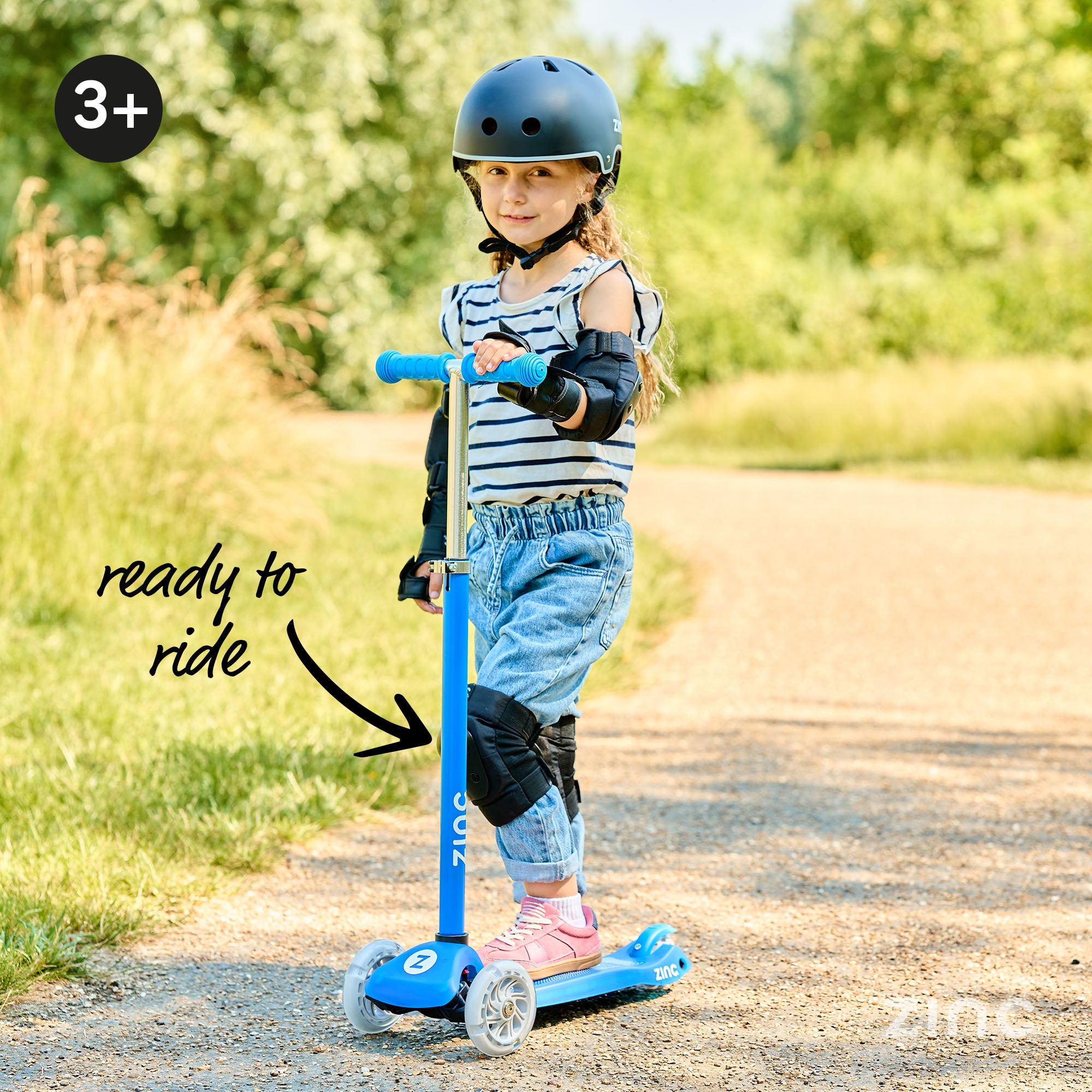 A blue three-wheeled Zinc Superstar non-folding scooter being used by child wearing helmet. 