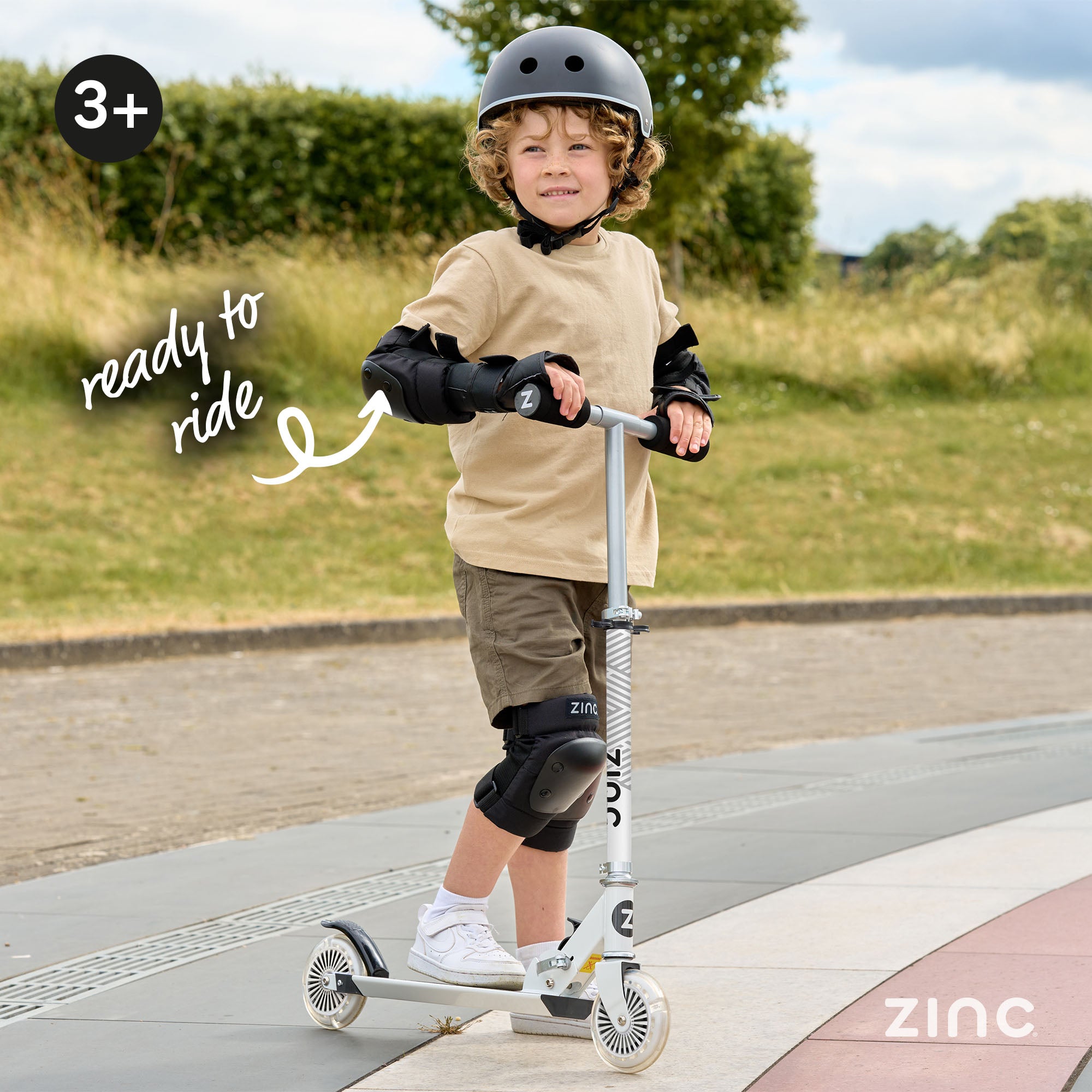 Child wearing helmet and protective pads while riding Zinc Rider folding scooter demonstrating proper safety equipment