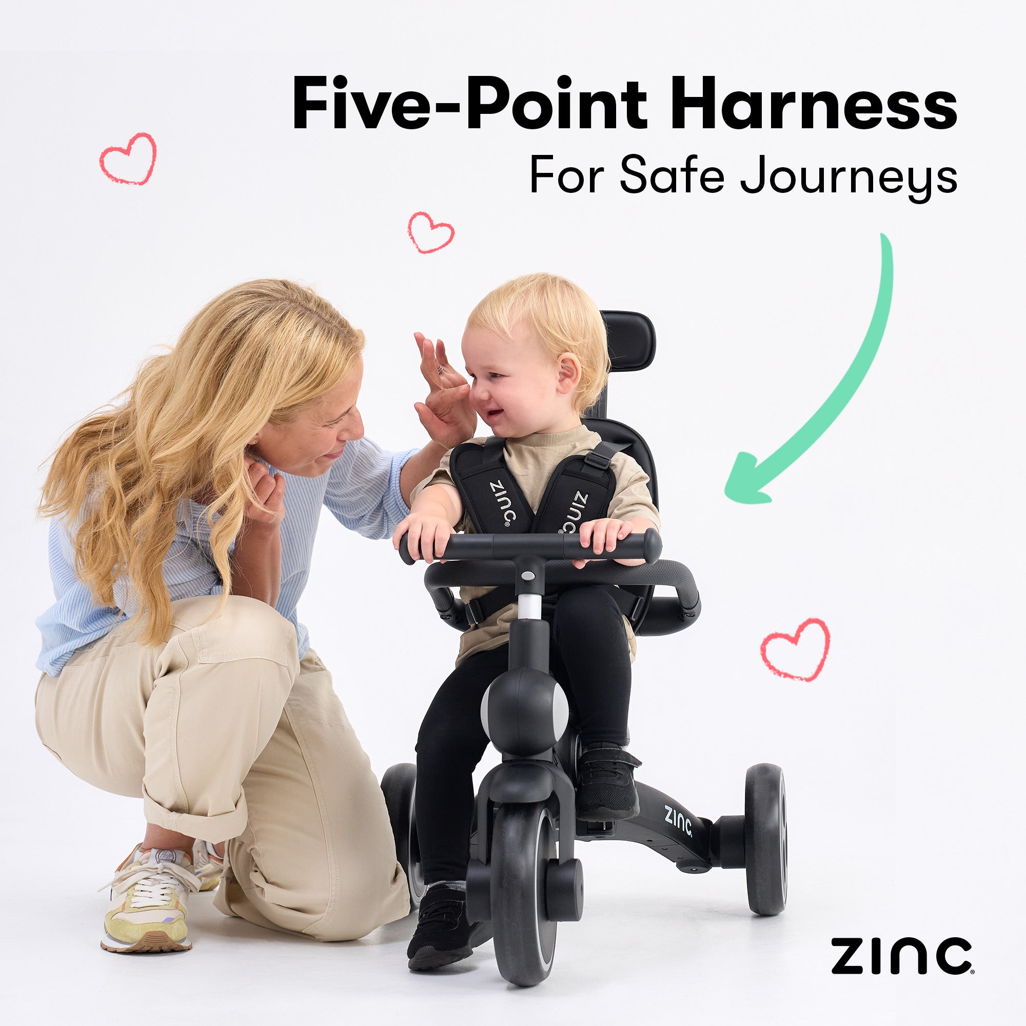 Child on a tricycle with a five-point harness, assisted by a woman, with 'Zinc' branding.