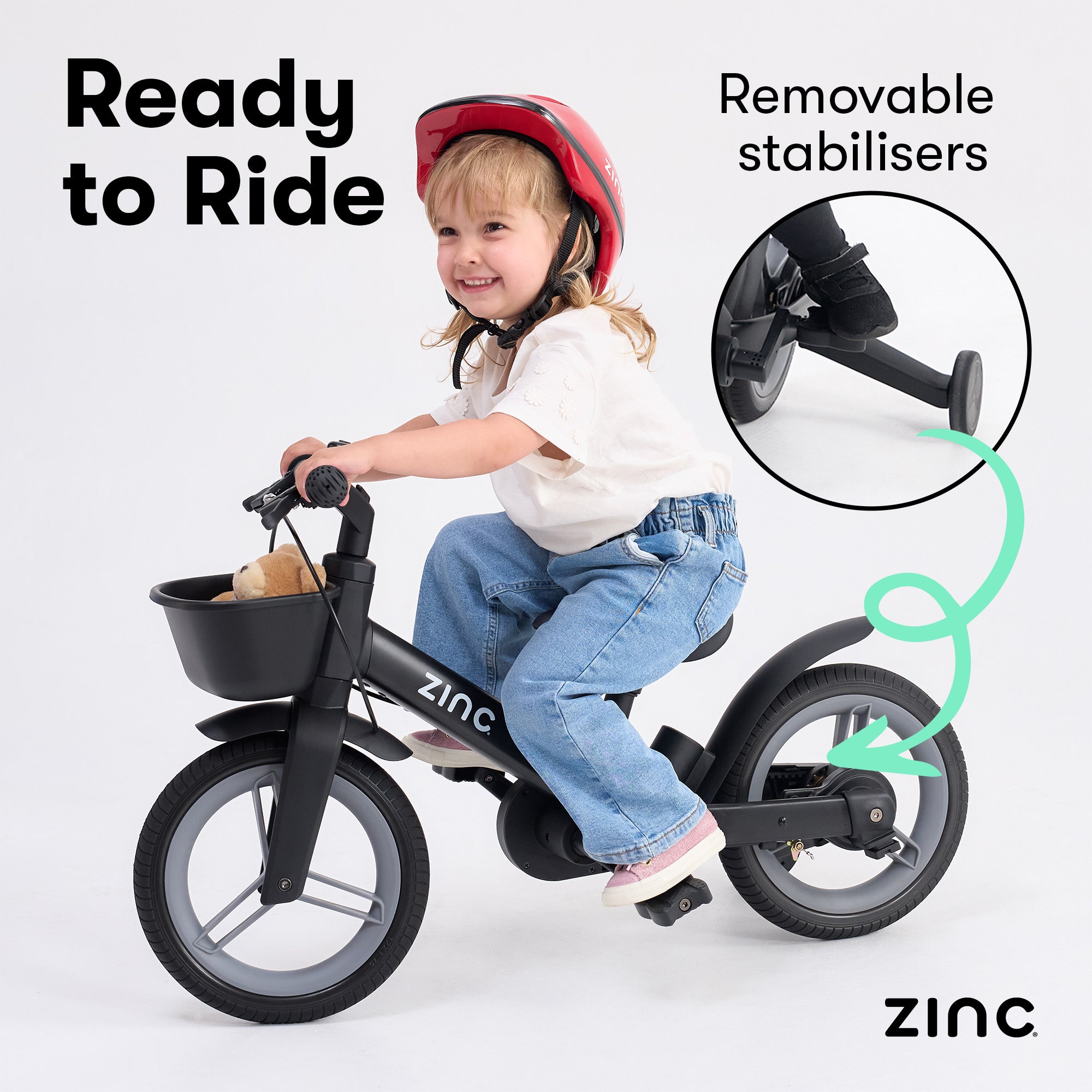 Child riding a Zinc balance bike with removable stabilizers, featuring a storage basket on the front.