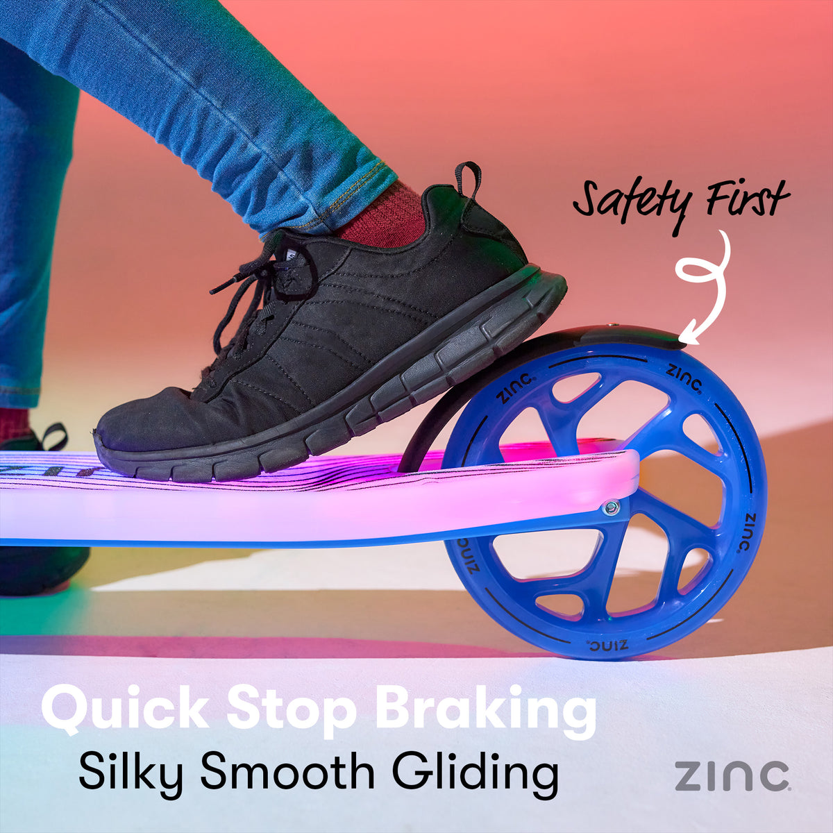 A close-up of a person's foot in a black shoe resting on a LED light up deck, with the wheel of a zinc-branded scooter visible. Text on the image highlights 'Safety First' and 'Quick Stop Braking Silky Smooth Gliding'.