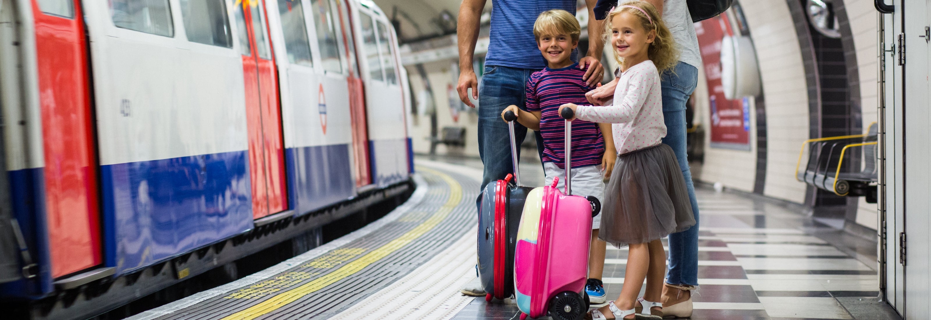 Happy boy standing on train platform edge with his Flyte scooter suitcase.